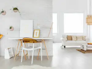 A minimal home office with a white desk, wooden chair, and hanging planters sits within a bright living area. Perfect for those seeking stylish real estate properties in Ulcinj, Montenegro by Ekosphere.