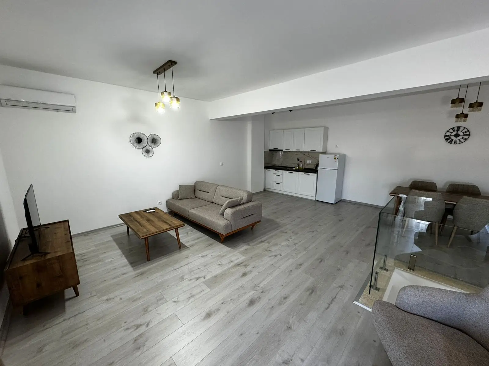 Stylish open-plan living in Ulcinj: gray sofa, modern kitchen, wood accents. Invest with immorenta.me by Ekosphere doo.
