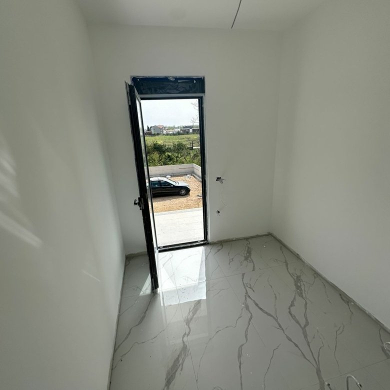 Bright, modern room with marble-tiled floor and white walls; direct access to parking. Prime Ulcinj property by ekosphere doo.