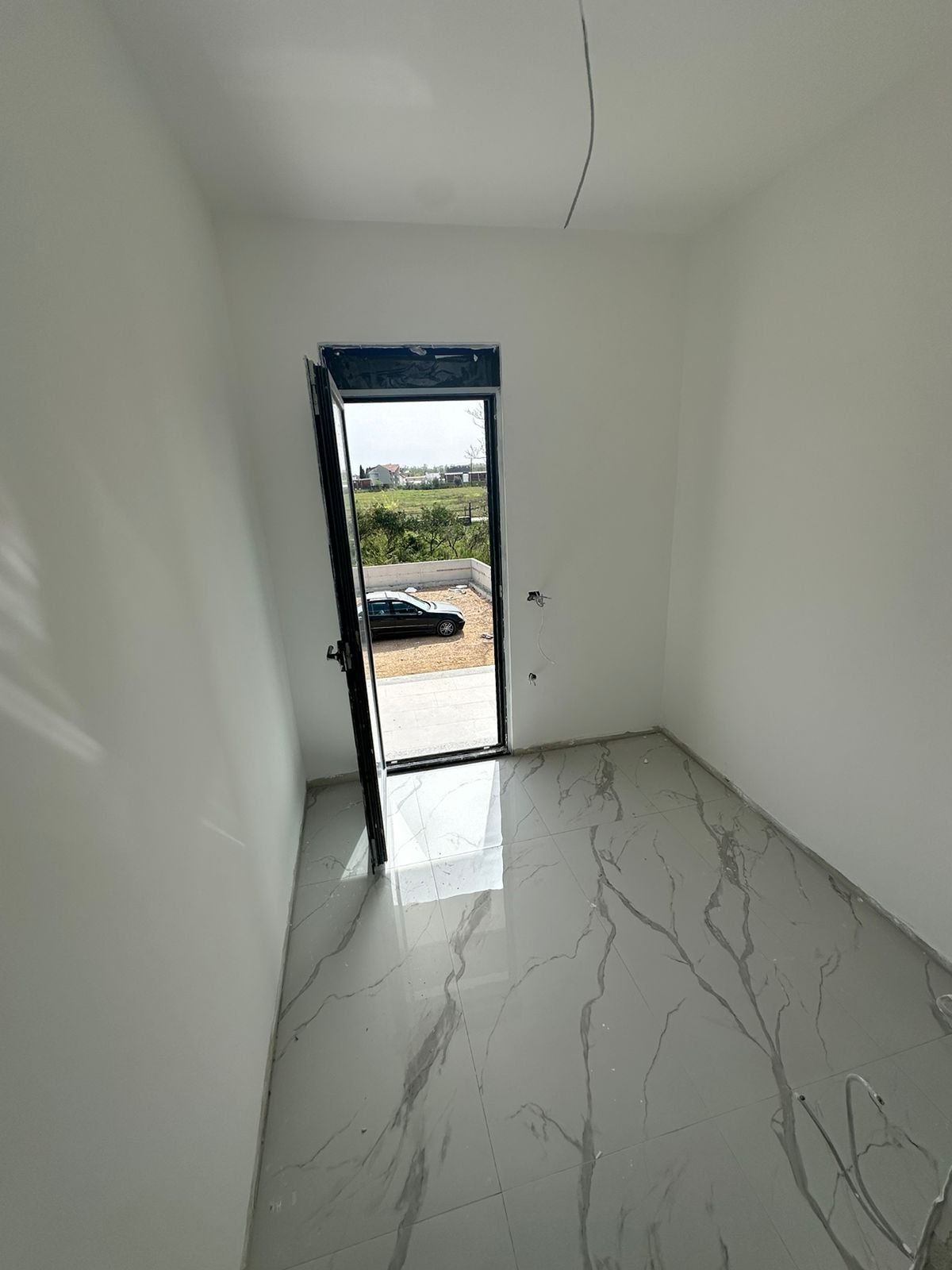 Bright, modern room with marble-tiled floor and white walls; direct access to parking. Prime Ulcinj property by ekosphere doo.