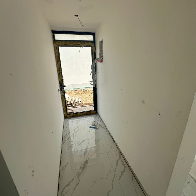 Investment opportunity in Ulcinj: unfinished hallway with white walls, glossy tiles, and doorway&mdash;listed by immorenta.me.