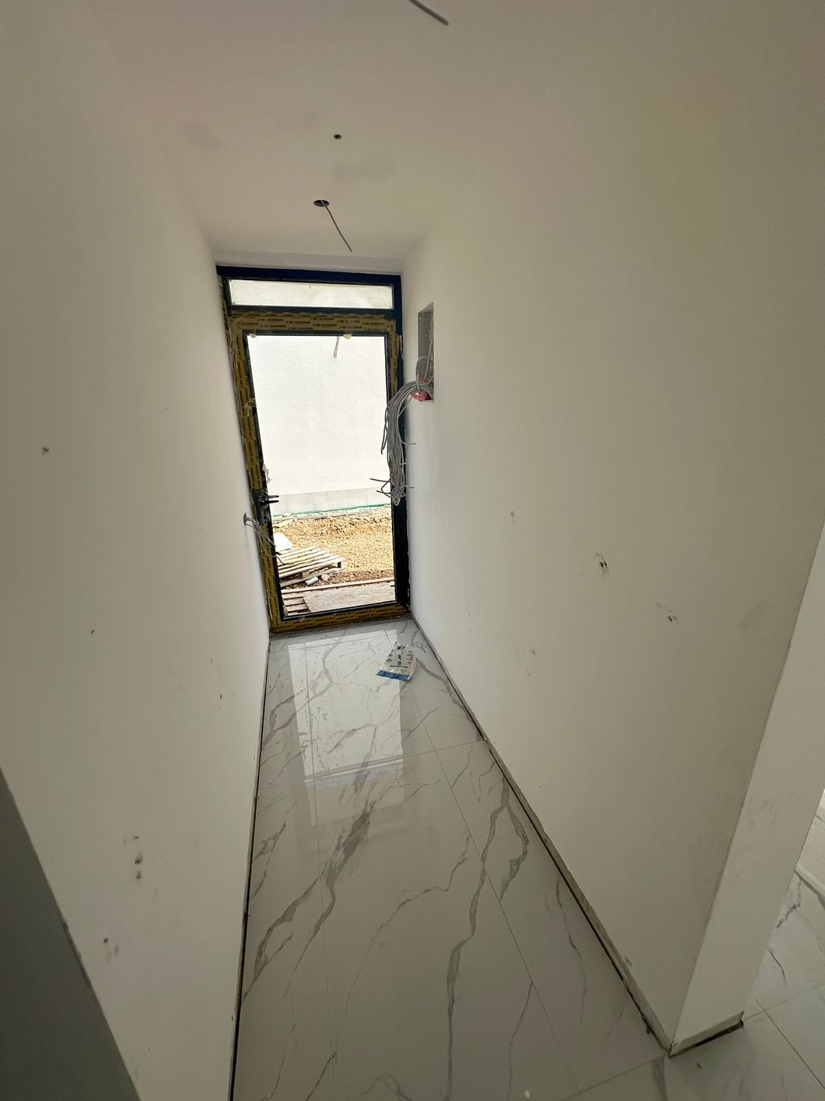 Investment opportunity in Ulcinj: unfinished hallway with white walls, glossy tiles, and doorway&mdash;listed by immorenta.me.