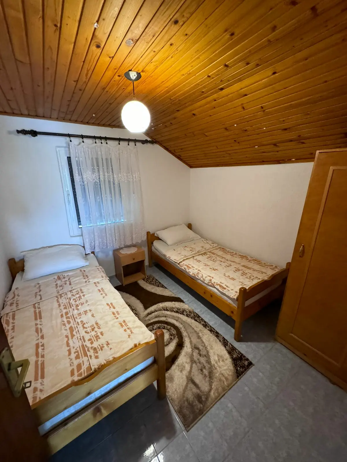 Inviting Ulcinj bedroom with wooden ceilings, twin beds, and eco-friendly Ekosphere style; ideal Montenegro property investment.