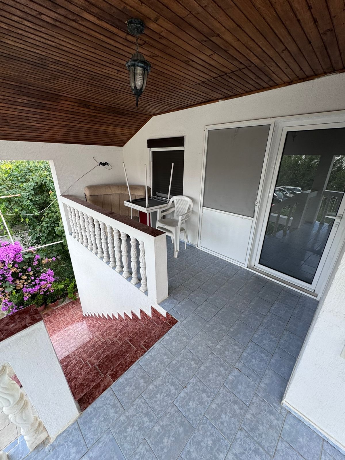 Spacious covered balcony with tiled flooring, white railings, and garden decor&mdash;perfect Ulcinj investment via immorenta.me by ekosphere doo.