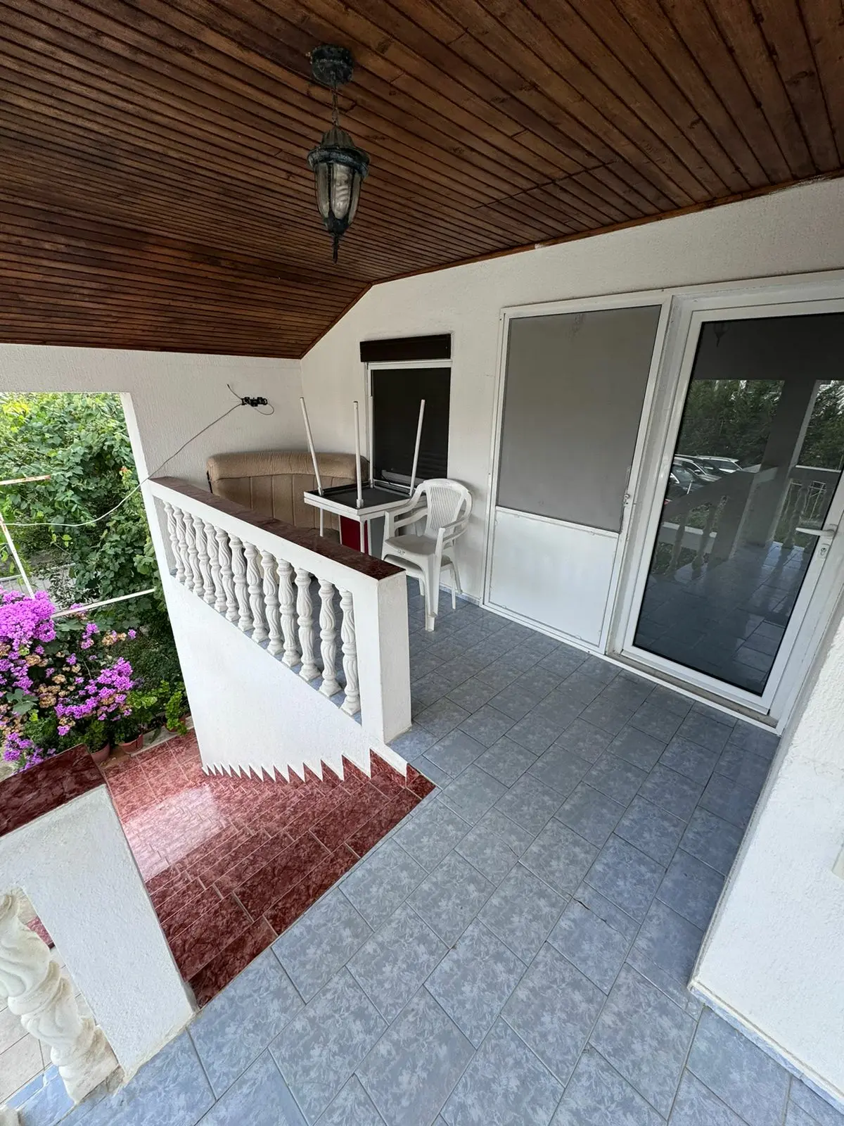 Spacious covered balcony with tiled flooring, white railings, and garden decor&mdash;perfect Ulcinj investment via immorenta.me by ekosphere doo.