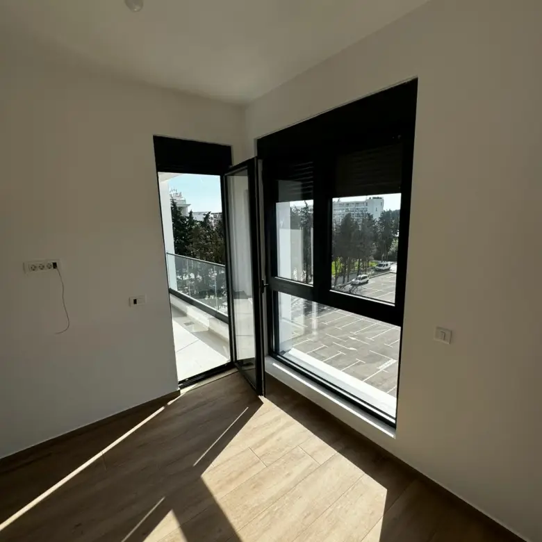 Bright, modern room in Ulcinj with wood floors and balcony access&mdash;invest in Montenegro real estate via immorenta.me by ekosphere doo.