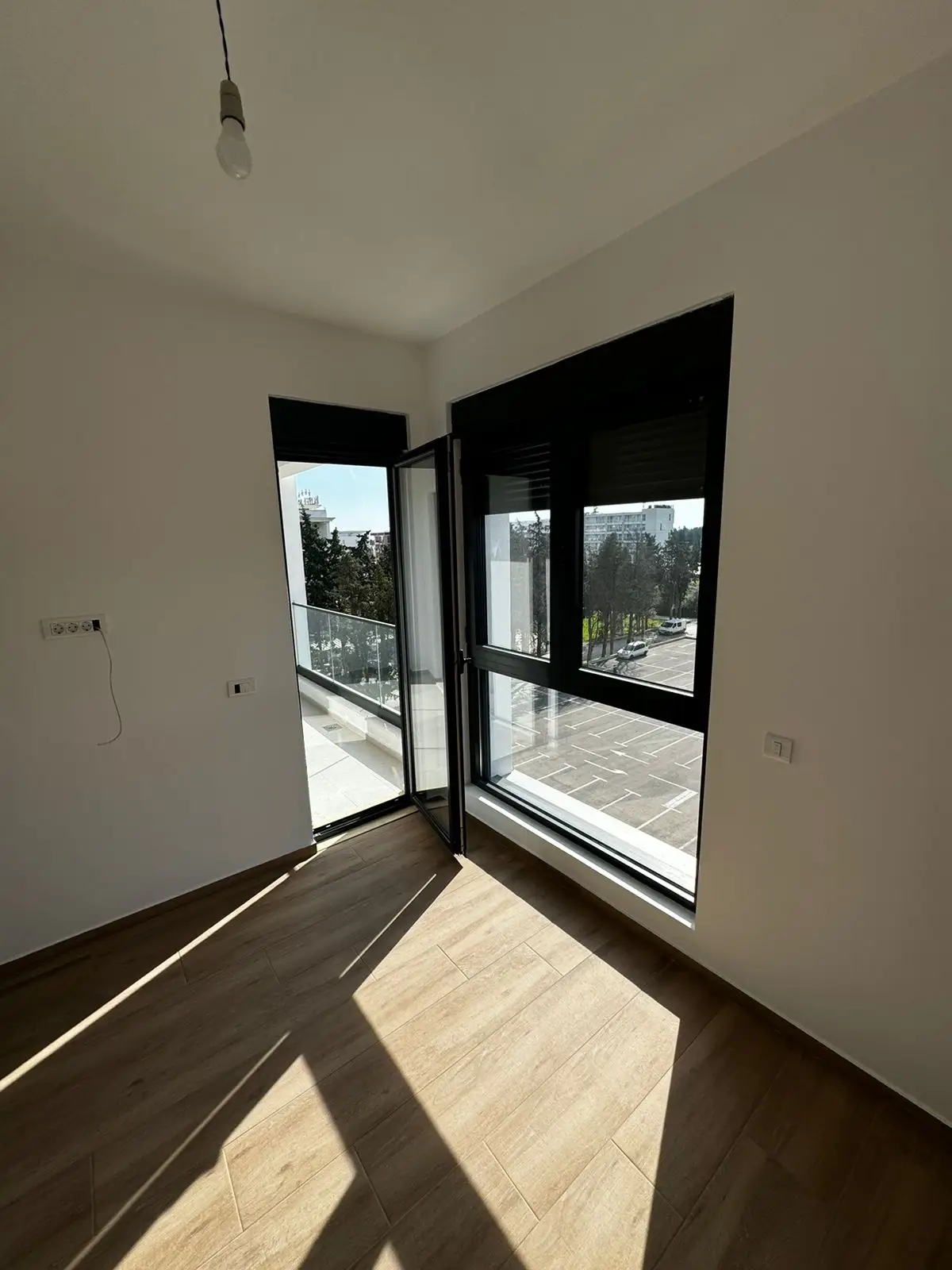 Bright, modern room in Ulcinj with wood floors and balcony access&mdash;invest in Montenegro real estate via immorenta.me by ekosphere doo.
