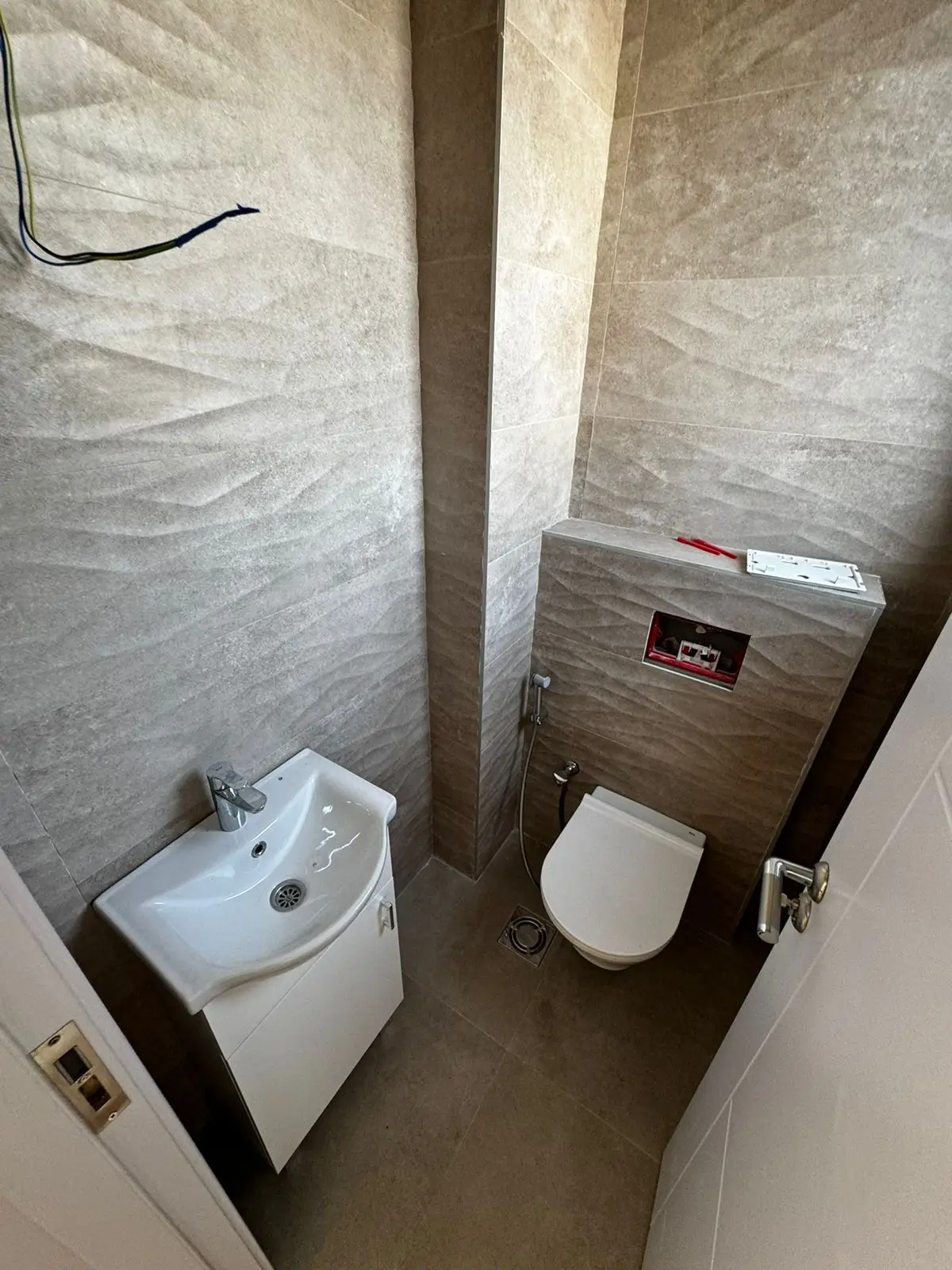Stylish modern bathroom in Ulcinj, Montenegro&mdash;beige tiles, wall toilet, sink cabinet; ideal investment via immorenta.me (EkoSphere).