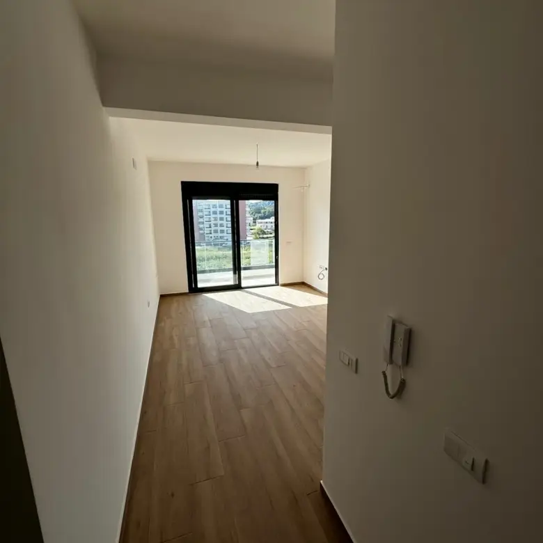 Modern empty room with white walls, wood floors, balcony and panoramic Ulcinj views&mdash;exclusive listing on immorenta.me by ekosphere doo.
