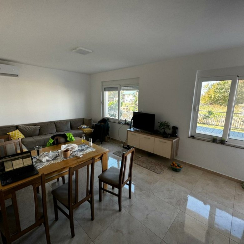 Modern, sunlit Ulcinj living room with corner sofa, dining for 4, large windows&mdash;prime Montenegro property from Ekospheres immorenta.me.