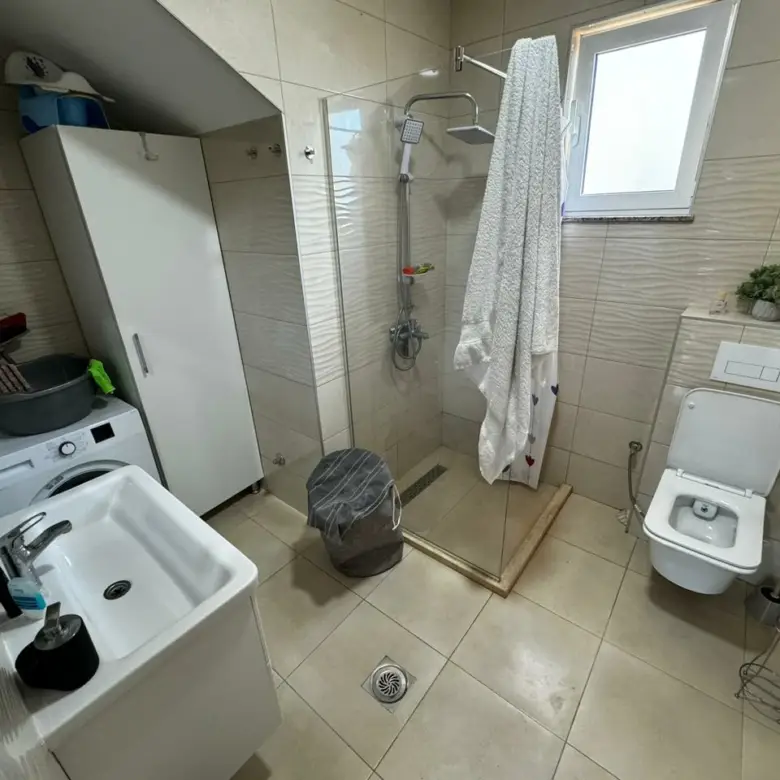 Modern bathroom in Ulcinj property with beige tiles, glass shower, premium fixtures&mdash;exclusive listing on immorenta.me by Ekosphere.