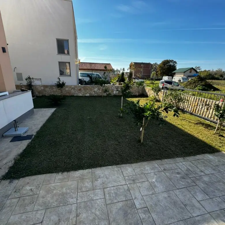 Modern white property with manicured lawn and tiled patio in Ulcinj, top real estate from immorenta.me by ekosphere doo.