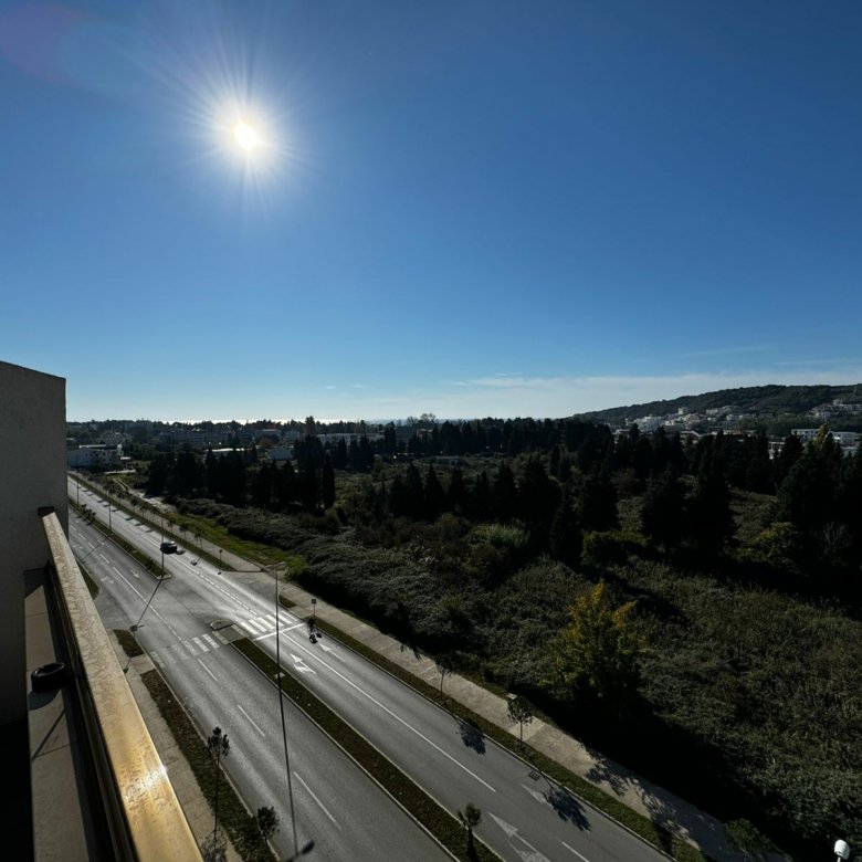 Bright balcony view in Ulcinj, Montenegro with lush greenery, clear sky, and quiet road&mdash;ideal for prime real estate investment. Powered by ekosphere doo via immorenta.me.