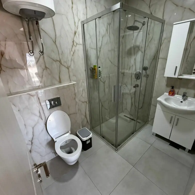 Luxury bathroom in Ulcinj with marble walls, glass shower, modern fixtures&mdash;ideal real estate investment via immorenta.me.