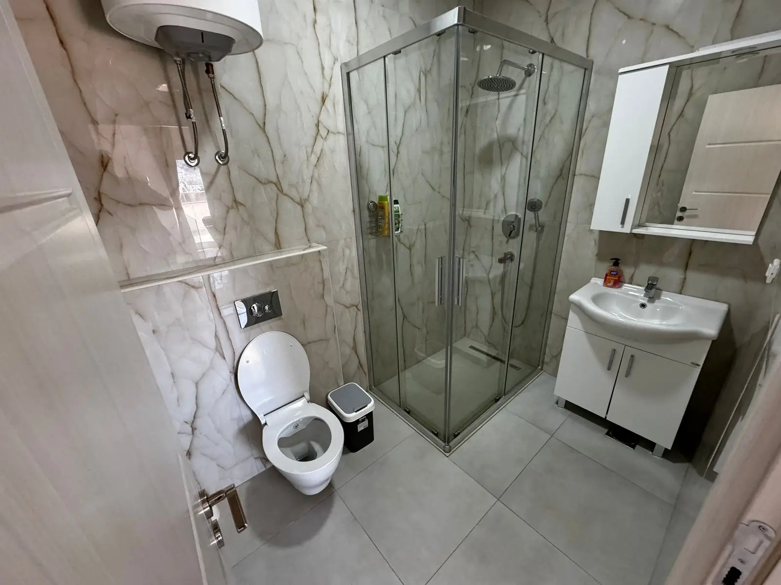 Luxury bathroom in Ulcinj with marble walls, glass shower, modern fixtures&mdash;ideal real estate investment via immorenta.me.