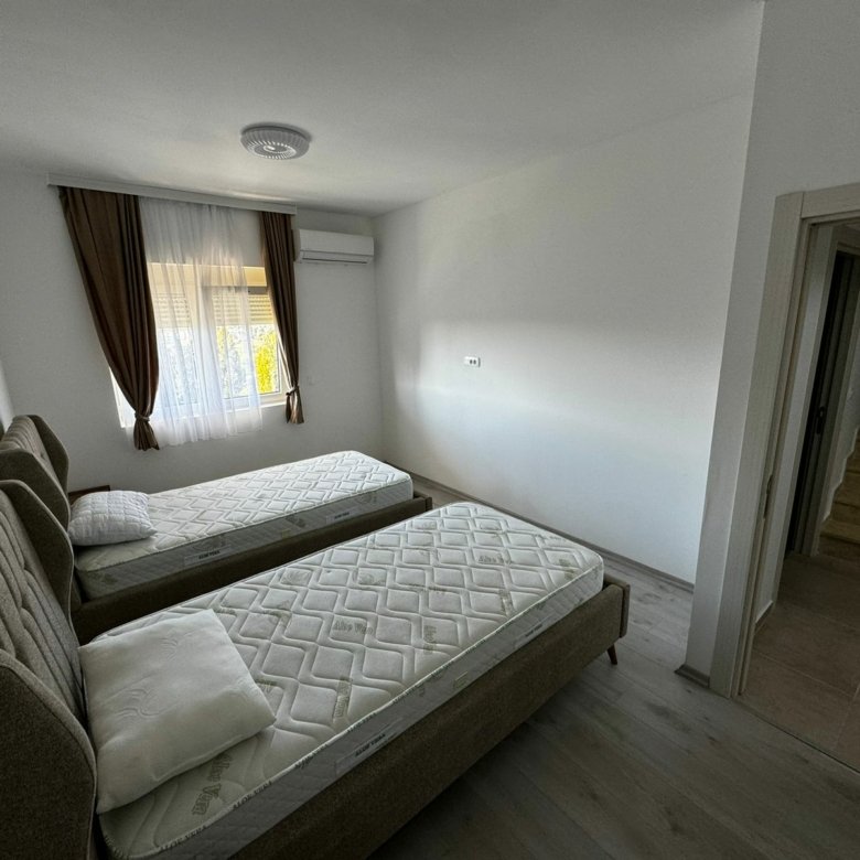 Modern Ulcinj bedroom with two single beds, AC, window, brown curtains; prime investment from Ekosphere&rsquo;s immorenta.me.