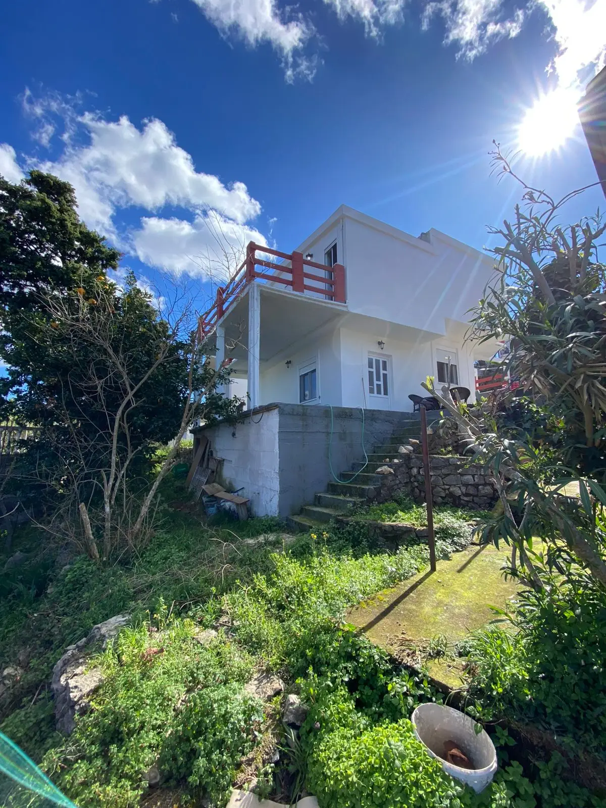 Stunning two-story white house with red balcony, sunlit yard on a grassy slope&mdash;prime Ulcinj real estate via immorenta.me by ekosphere doo.
