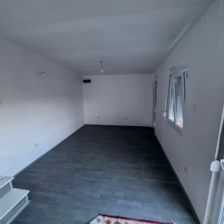 Modern investment opportunity in Ulcinj: bright room with white walls, dark floors, stairs, 3 windows, and glass door by ekosphere.