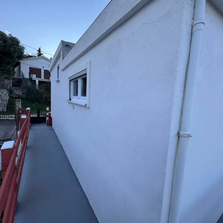 Modern white building with window, red railing, and walkway in Ulcinj, Montenegro&mdash;prime real estate by Ekosphere & immorenta.me.