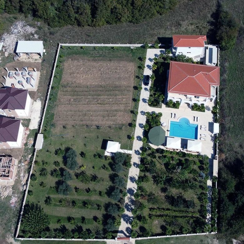 Prime Ulcinj real estate: garden, pool, red-roofed villa, Ekosphere homes under construction amid lush greenery. immorenta.me.