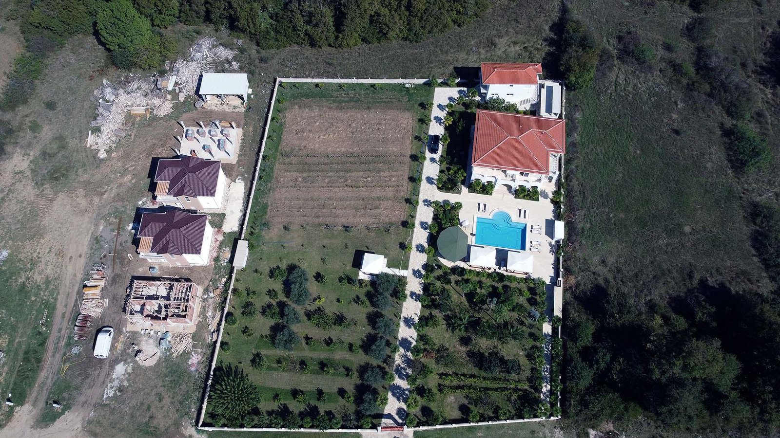 Prime Ulcinj real estate: garden, pool, red-roofed villa, Ekosphere homes under construction amid lush greenery. immorenta.me.
