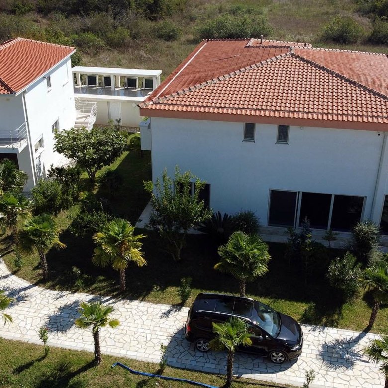 Exclusive aerial view of a luxury white villa with pool, palm trees, and lush Ekosphere landscaping in Ulcinj&mdash;listed on immorenta.me.