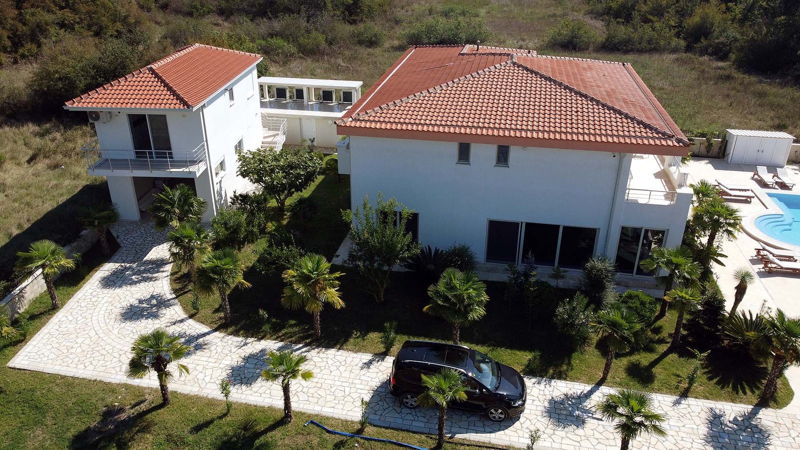 Exclusive aerial view of a luxury white villa with pool, palm trees, and lush Ekosphere landscaping in Ulcinj&mdash;listed on immorenta.me.