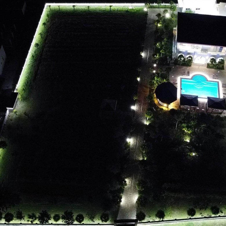 Stunning aerial night view of an illuminated Ulcinj property with pool, gardens&mdash;prime investment via Montenegro-Listings.me by Ekosphere.