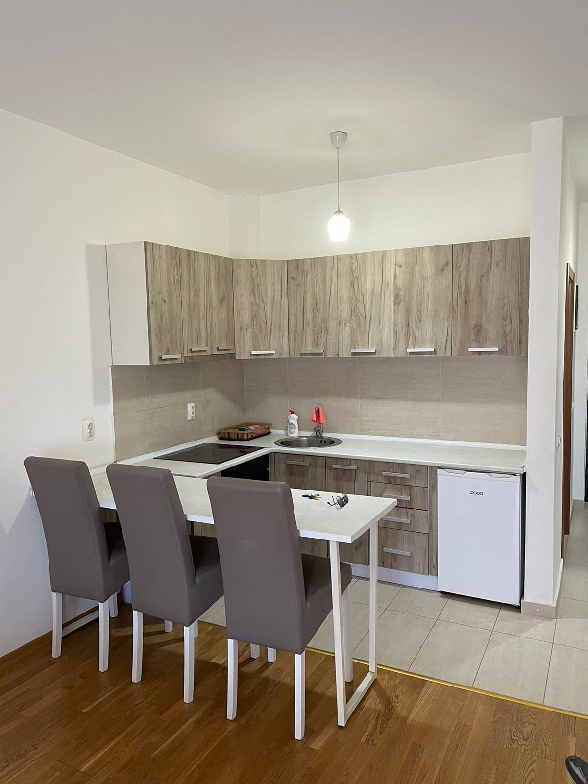 Contemporary kitchen in Ulcinj, Montenegro: sleek wood cabinets, appliances, and bar seating. Ideal real estate by Ekosphere DOO.