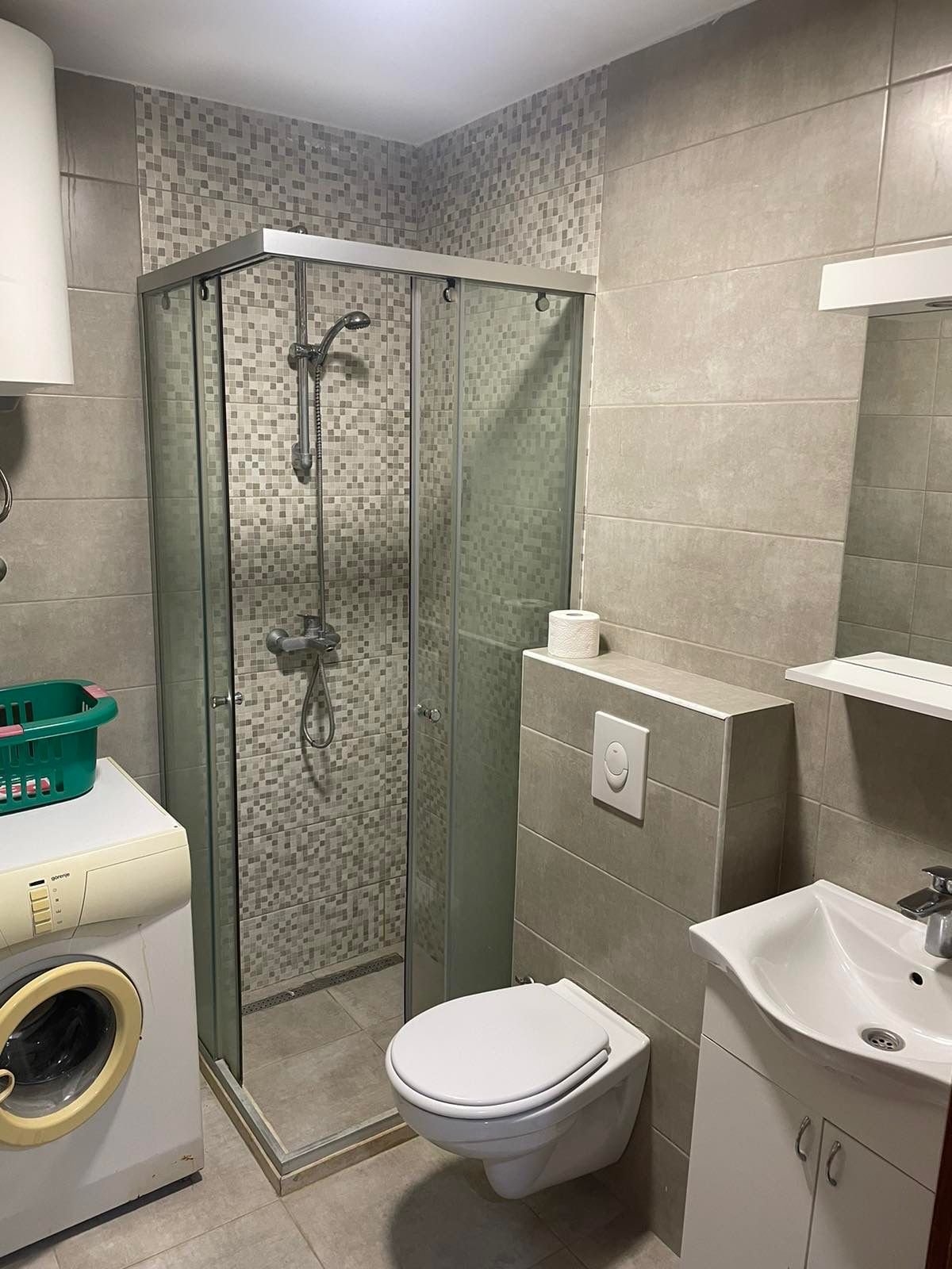 Modern bathroom in Ulcinj with glass shower, wall toilet, washer, stylish sink. Invest in Montenegro via immorenta.me by ekosphere doo.