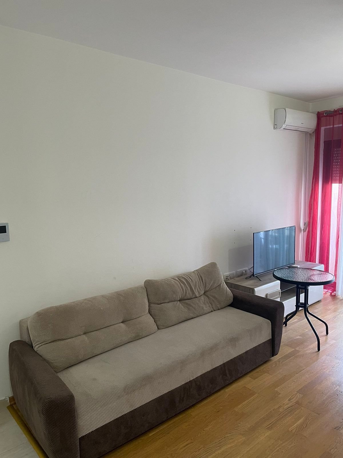 Stylish Ulcinj apartment for sale: modern sofa, glass table, red curtains, AC; ideal investment&mdash;see immorenta.me (ekosphere doo).