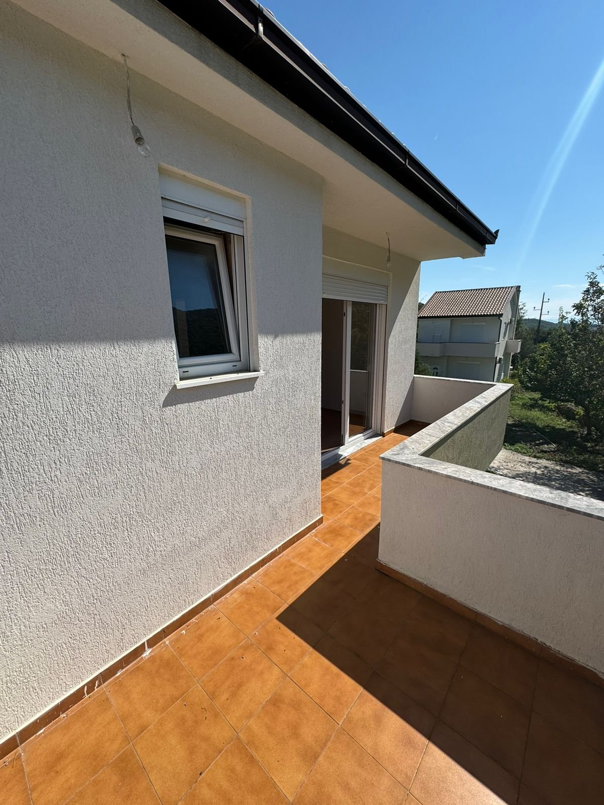 Bright balcony in Ulcinj, Montenegro with tiled floors, glass doors, and scenic views&mdash;top real estate by Ekosphere on immorenta.me.