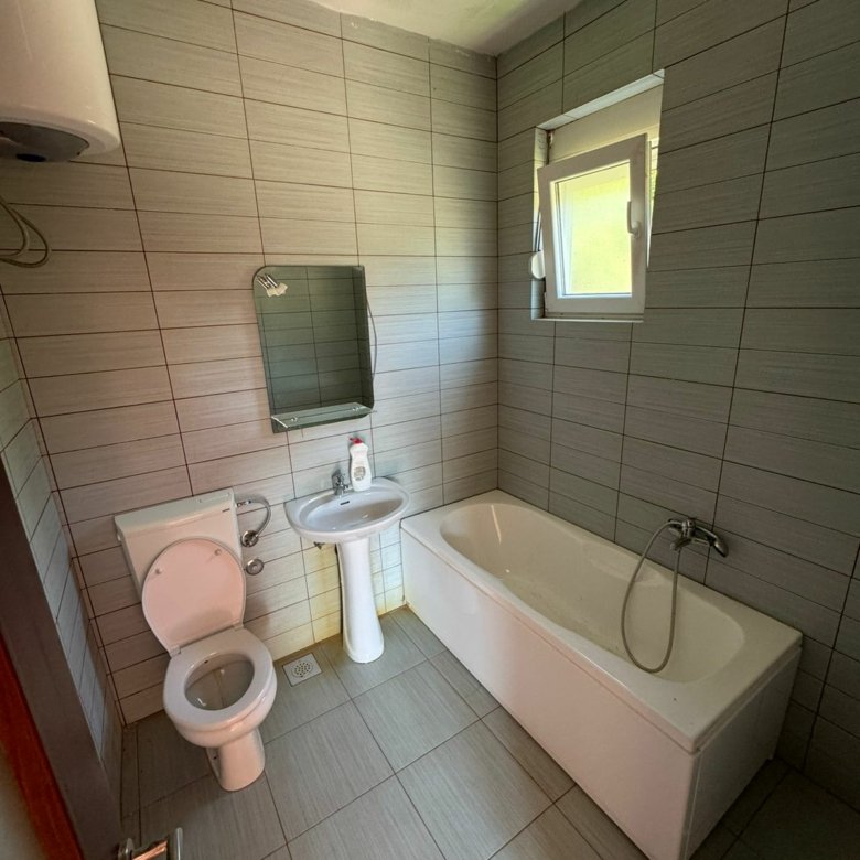 Modern bathroom in Ulcinj: light gray tiles, quality fixtures, bathtub & window&mdash;prime investment with immorenta.me by ekosphere doo.