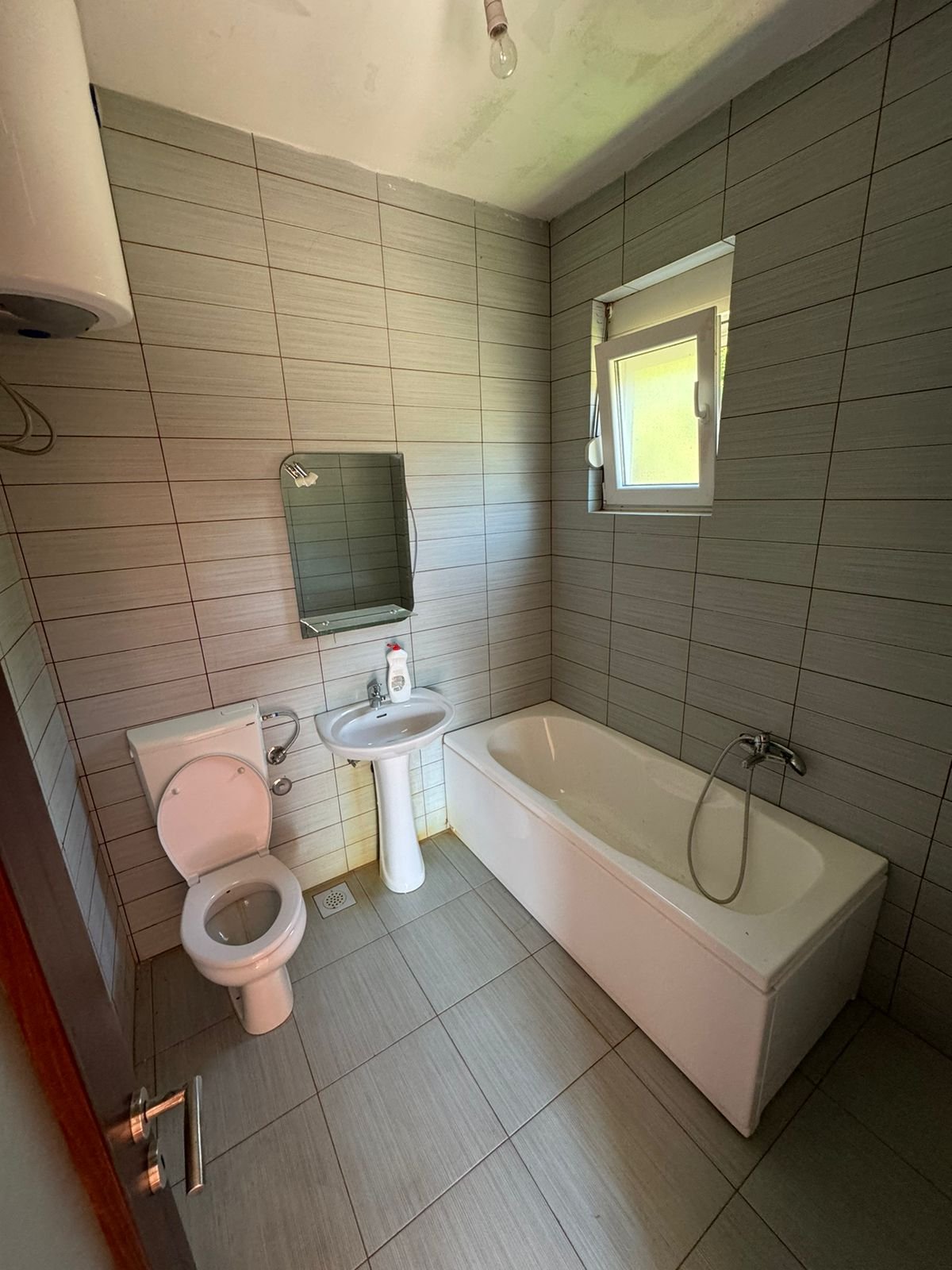 Modern bathroom in Ulcinj: light gray tiles, quality fixtures, bathtub & window&mdash;prime investment with immorenta.me by ekosphere doo.
