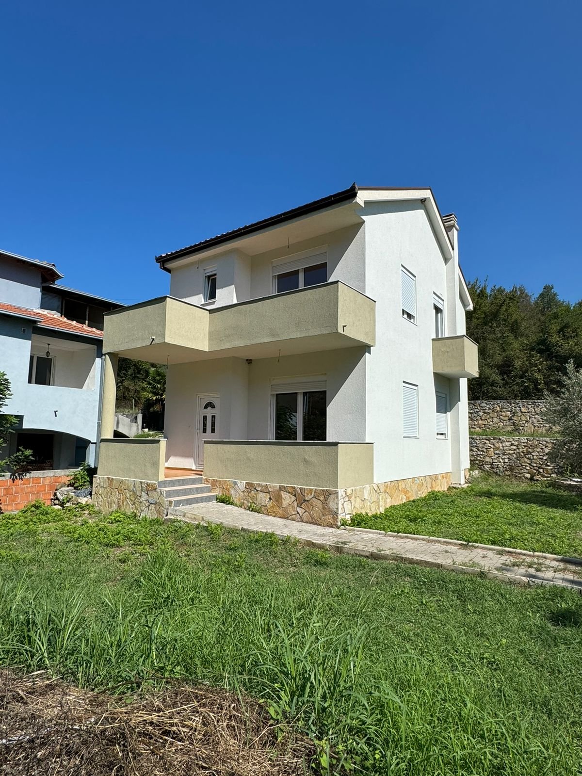 Stunning two-story white home with balconies and stone base in Ulcinj, Montenegro; ideal investment via immorenta.me by ekosphere doo.