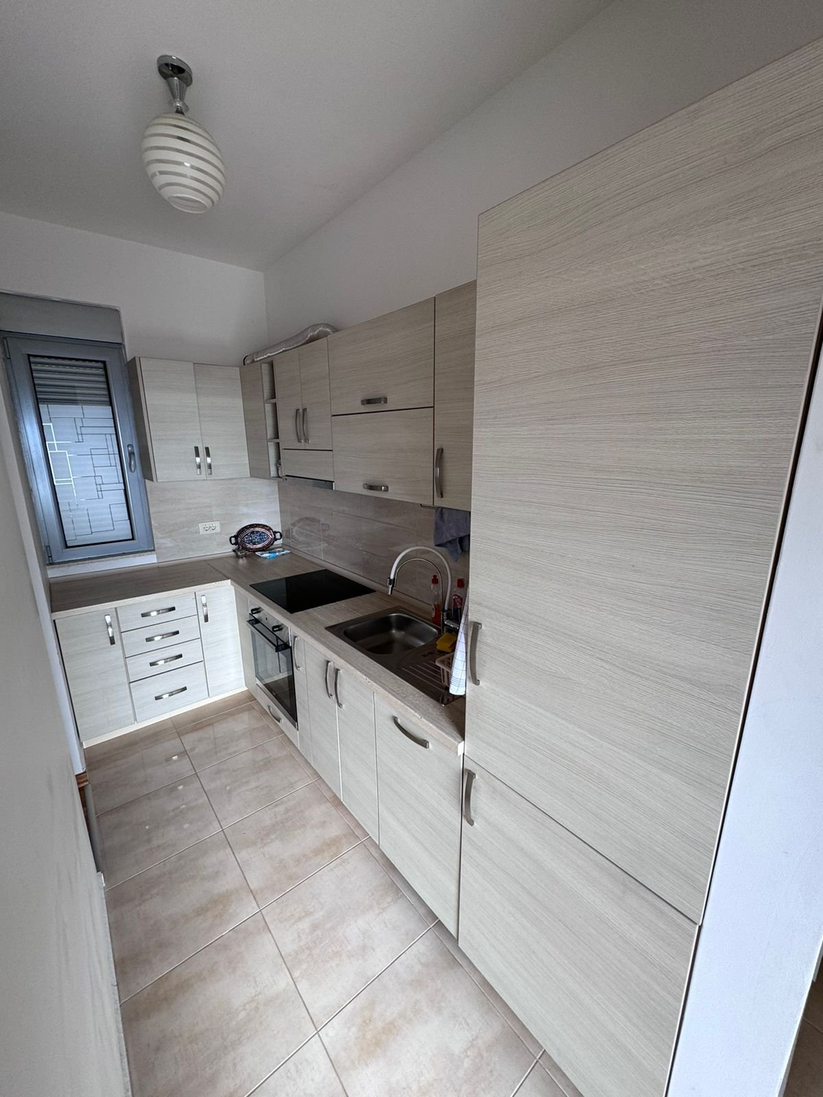 Modern narrow kitchen in Ulcinj with light wood cabinets, built-in oven, tiled floor&mdash;ideal investment on immorenta.me by ekosphere doo.