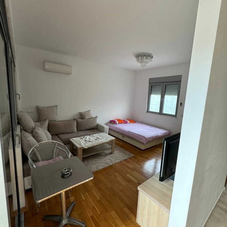 Modern, sunlit Ulcinj apartment with wood floors, cozy L-sofa, dining area, double bed by window&mdash;exclusive on Montenegro-Listings.me by Ekosphere doo.