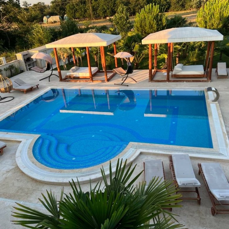 Luxurious pool oasis with blue tiles, lounge chairs, cabanas & chic seating&mdash;prime Ulcinj investment. Listed on immorenta.me.