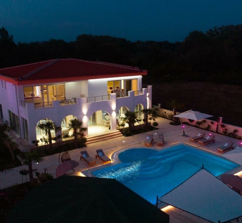 Stunning two-story white villa with red roof, balconies, pool, and lush ekosphere gardens&mdash;prime Ulcinj real estate by immorenta.me.