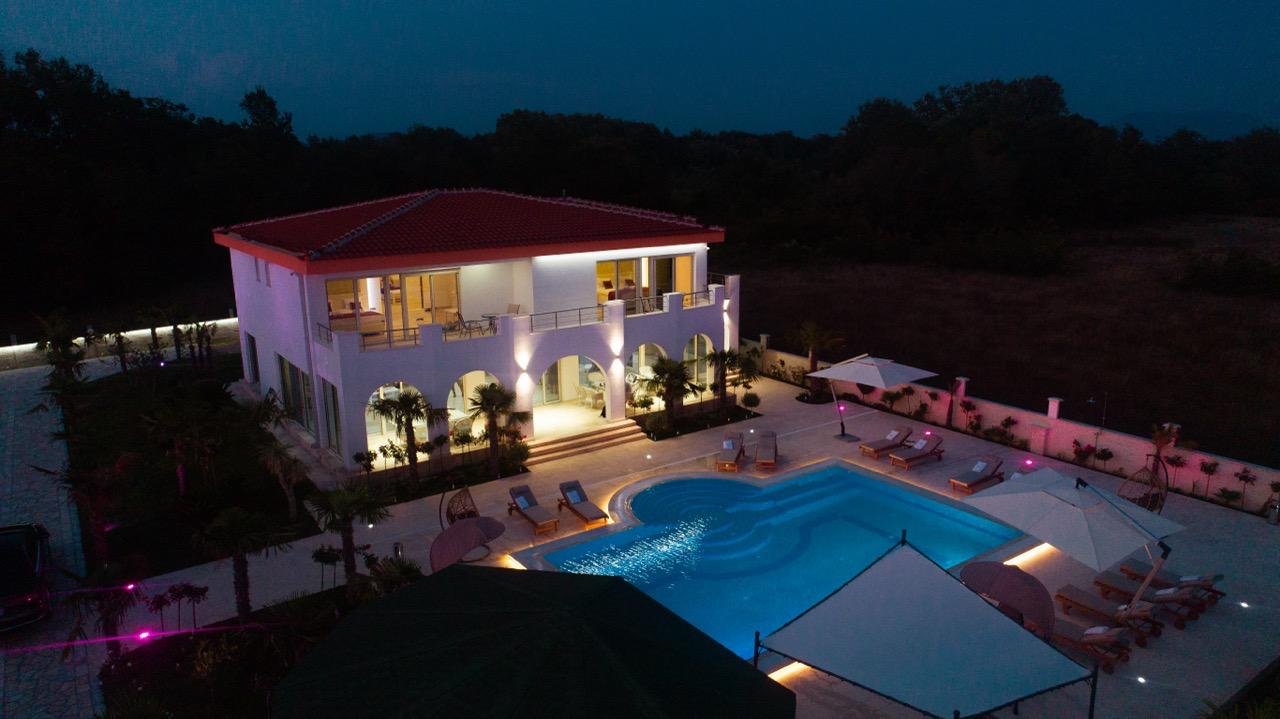 Stunning two-story white villa with red roof, balconies, pool, and lush ekosphere gardens&mdash;prime Ulcinj real estate by immorenta.me.