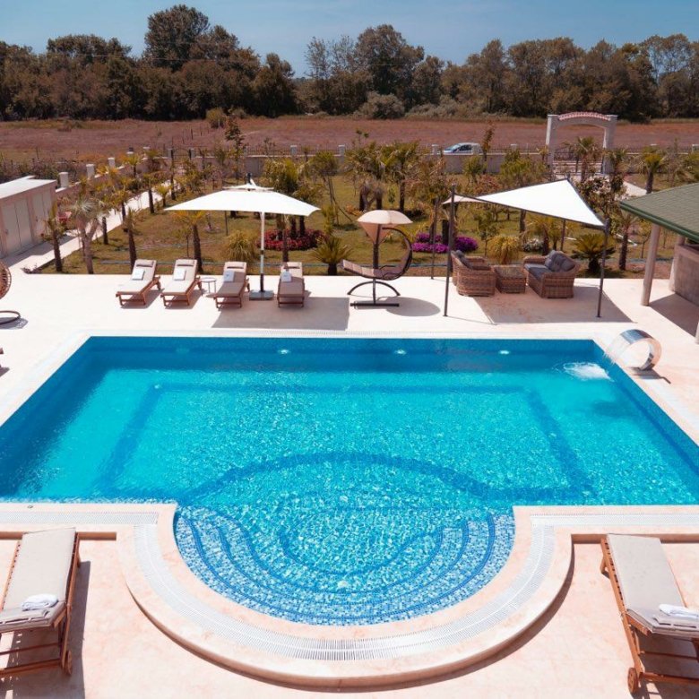 Luxurious pool with curved steps, lounge area, and scenic greenery&mdash;ideal Ulcinj property investment via immorenta.me by ekosphere doo.