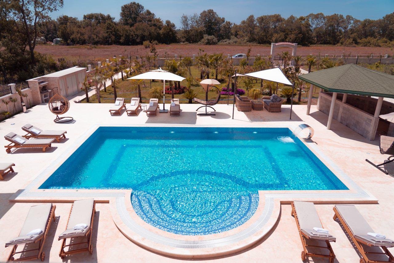 Luxurious pool with curved steps, lounge area, and scenic greenery&mdash;ideal Ulcinj property investment via immorenta.me by ekosphere doo.