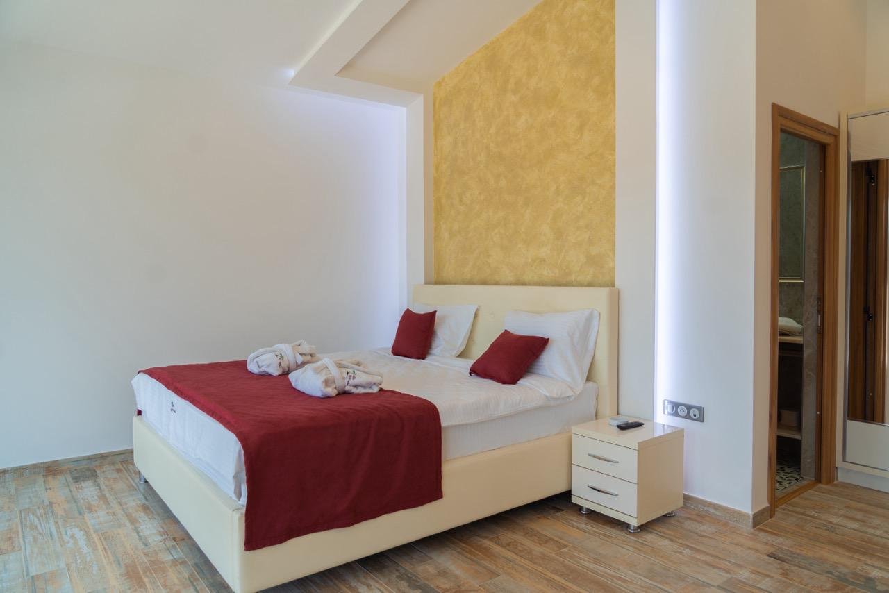 Elegant modern bedroom in Ekosphere, Ulcinj&mdash;double bed, white linens, red throw, wood floors. Invest via immorenta.me by ekosphere doo.