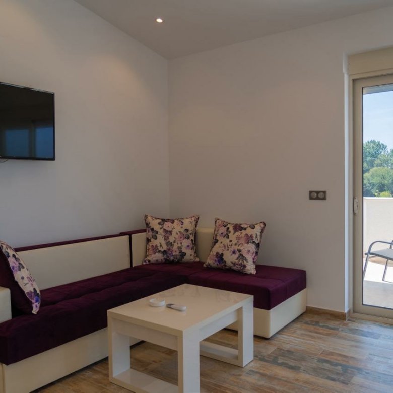 Stunning Ulcinj living room: elegant sofa, floral accents, balcony access&mdash;prime Montenegro investment from Ekosphere & immorenta.me.