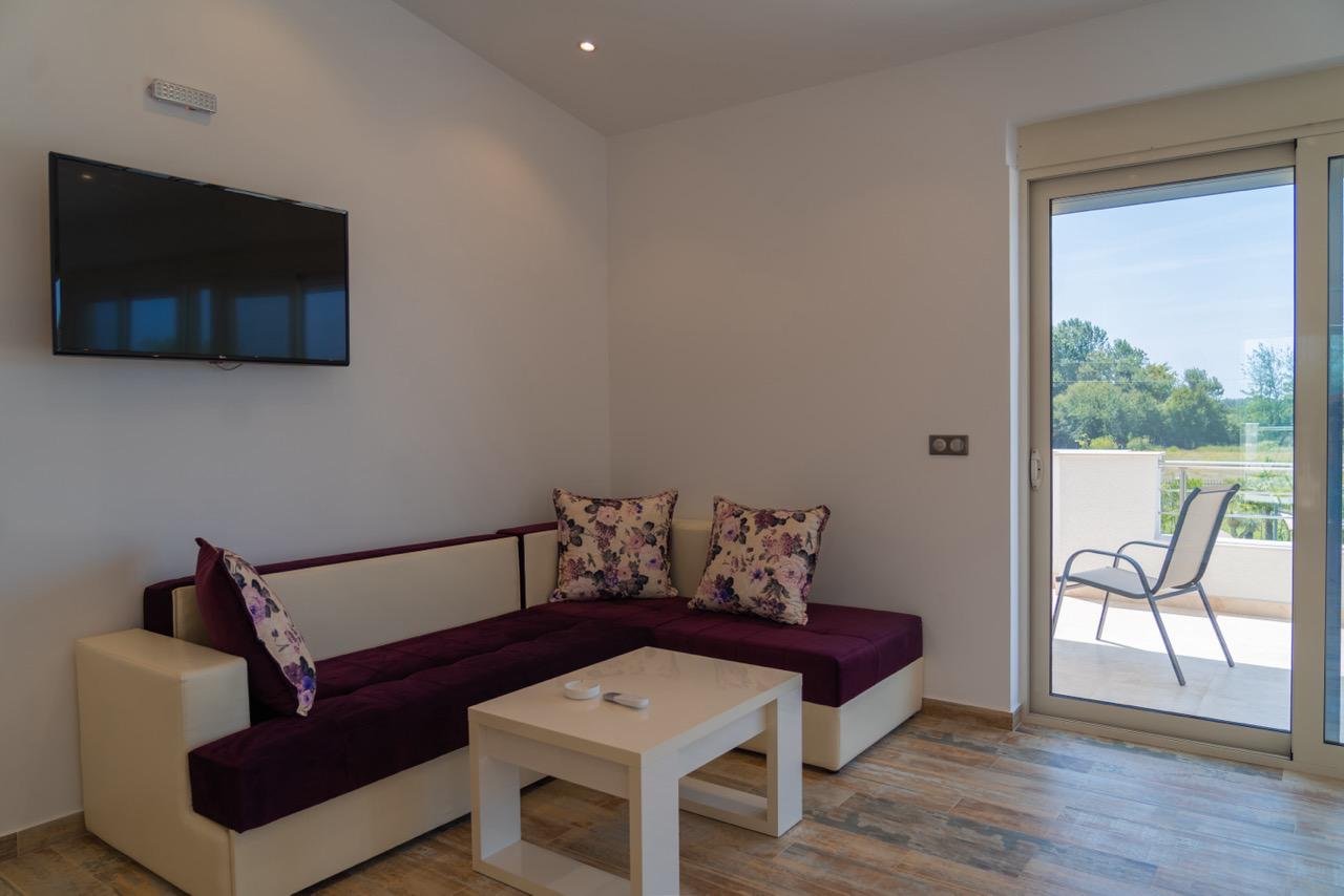 Stunning Ulcinj living room: elegant sofa, floral accents, balcony access&mdash;prime Montenegro investment from Ekosphere & immorenta.me.