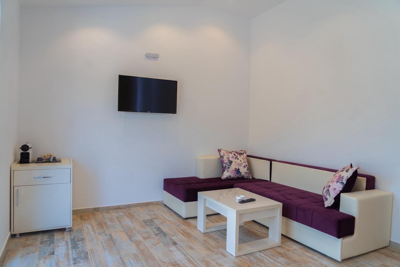 Contemporary Ulcinj Montenegro apartment: stylish sectional sofa, floral accents, sleek TV, wood floors&mdash;exclusive at immorenta.me by ekosphere doo.