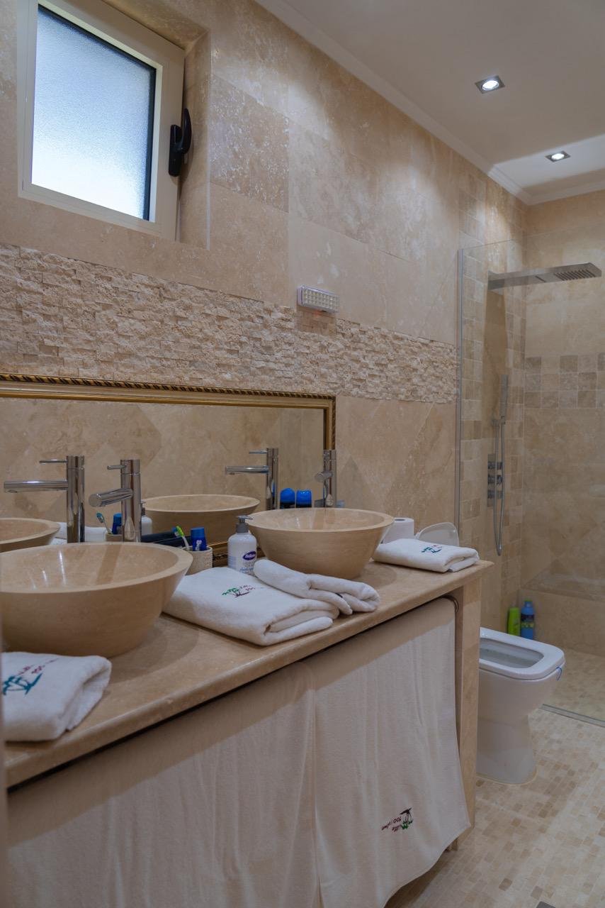 Elegant modern bathroom in Ulcinj real estate, tiled, dual vessel sinks, glass shower; exclusive on immorenta.me by ekosphere doo.