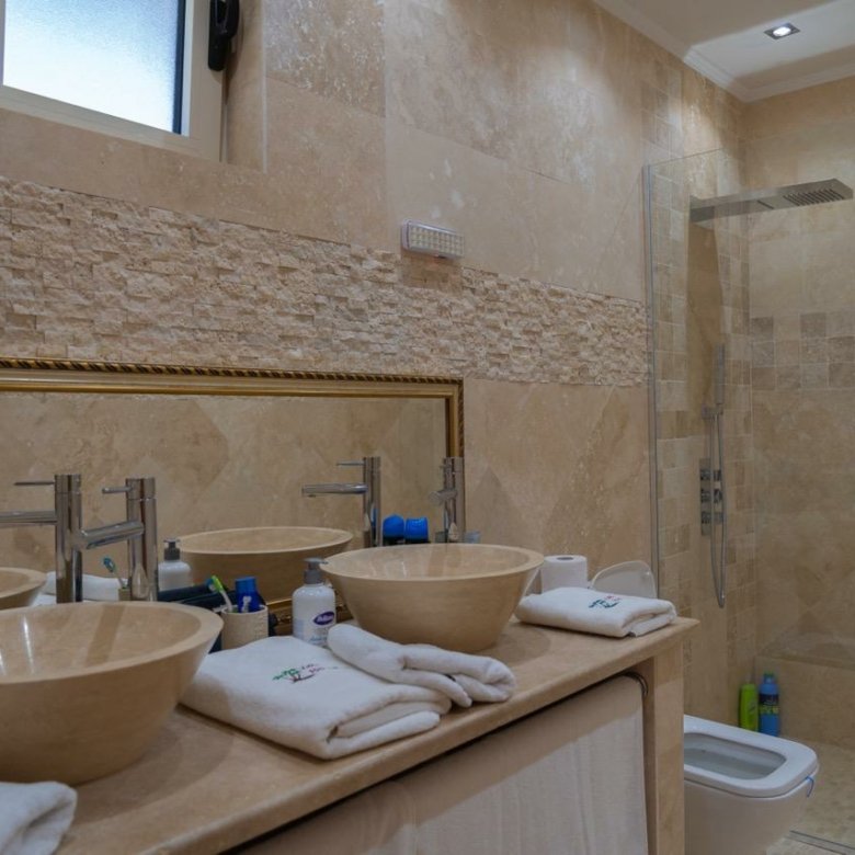 Luxury bathroom in Ulcinj, Montenegro: beige stone, double sinks, walk-in glass shower&mdash;exclusive Ekosphere/ immorenta.me property.