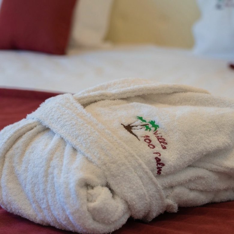 Luxurious folded white bathrobe on burgundy bedding in Ulcinj&mdash;exclusive comfort at Ekosphere DOO, via immorenta.me.