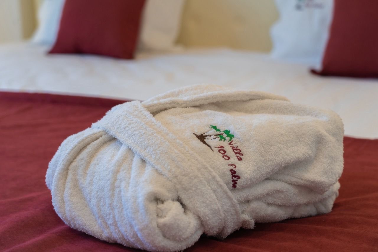 Luxurious folded white bathrobe on burgundy bedding in Ulcinj&mdash;exclusive comfort at Ekosphere DOO, via immorenta.me.